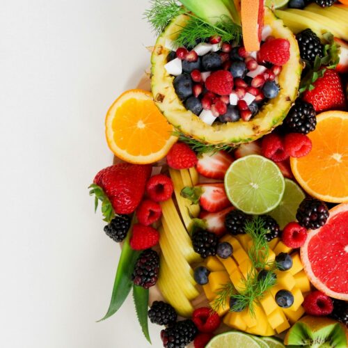 Colorful flat lay of assorted tropical fruits including pineapple, berries, and citrus.