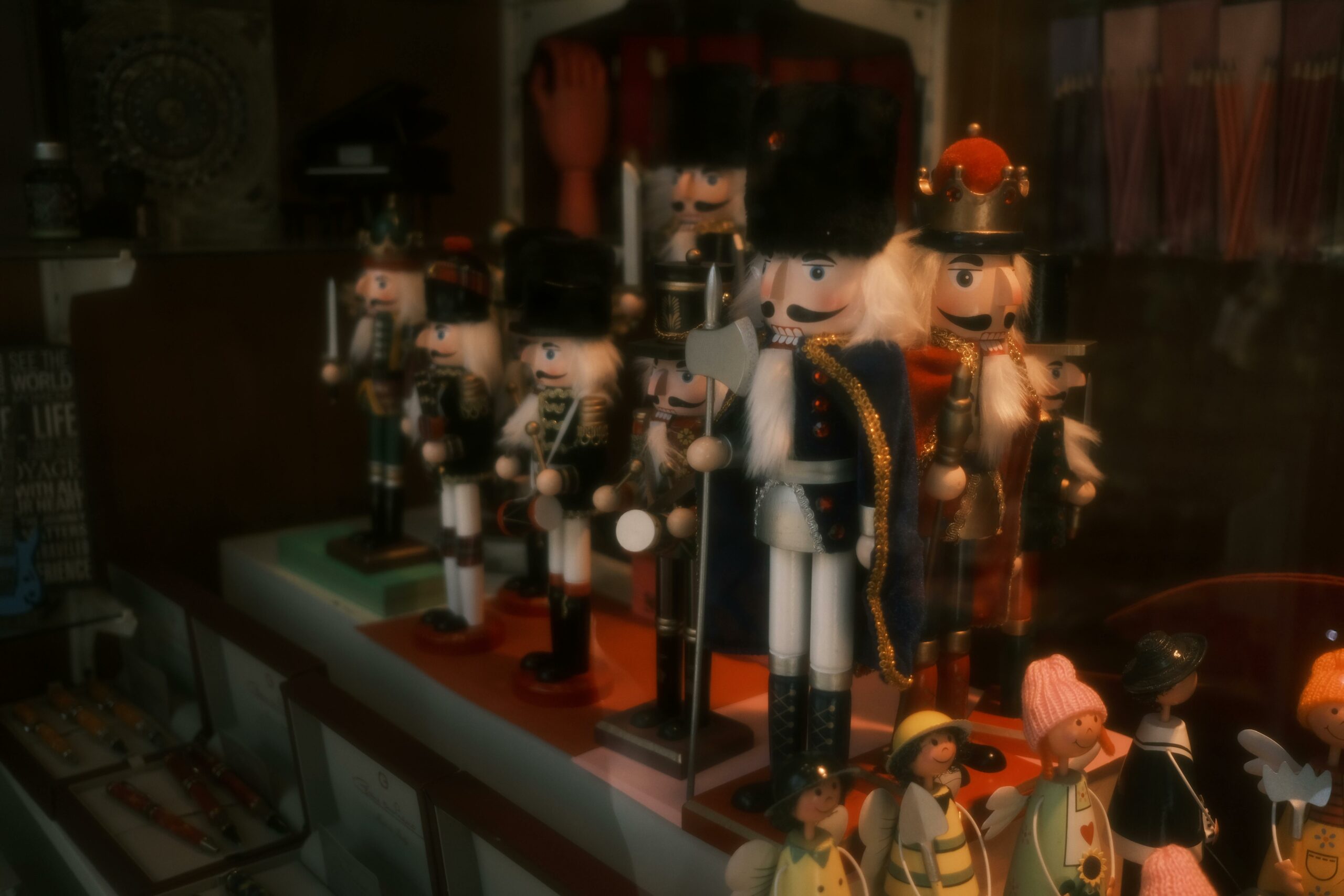 A collection of nutcracker figurines brightly displayed in a store window, evoking holiday charm.