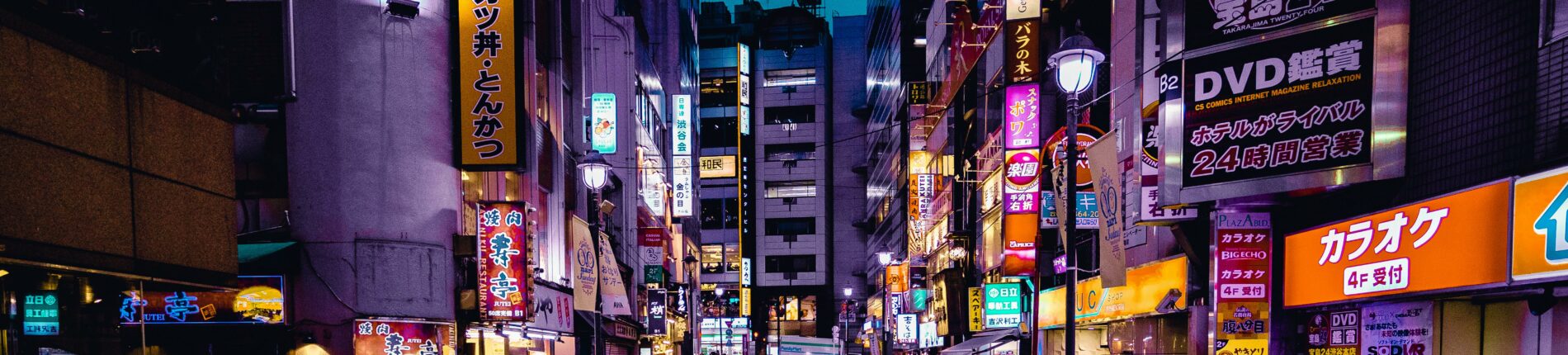 Explore the lively streets of Shinjuku, Tokyo at night with colorful lights and bustling activity.