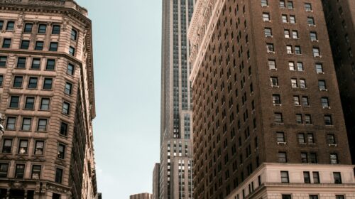 Bustling city life with iconic skyscraper under clear sky.