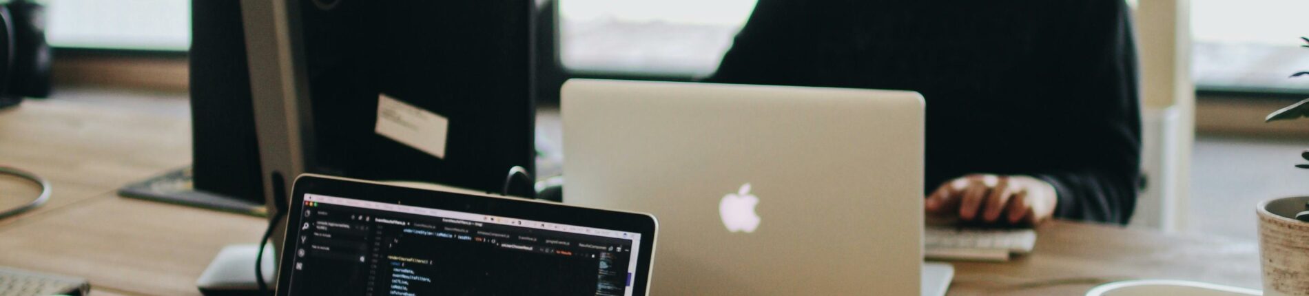 A web developer working on code in a modern office setting with multiple devices.