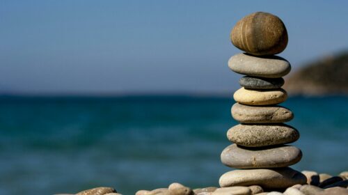 A stack of balanced stones on a beach with a tranquil ocean backdrop for meditation and zen.