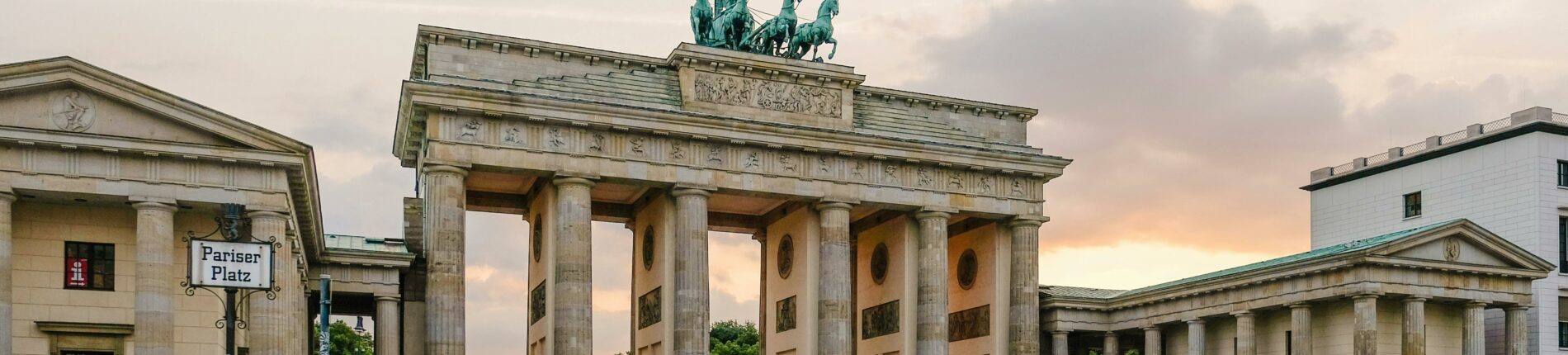 Scenic view of Berlin's Brandenburg Gate with people gathering at sunset.