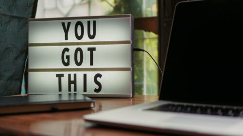 Lit sign with 'You Got This' alongside laptop on office desk.