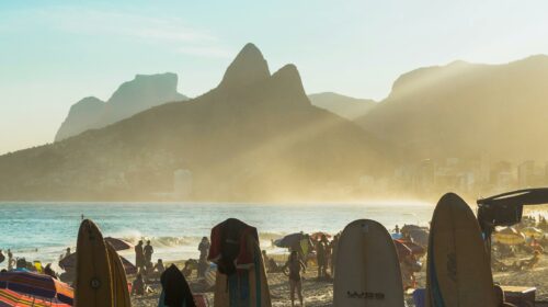 Surfboards lined up on Ipanema Beach in Rio de Janeiro at sunset with mountains in the background.