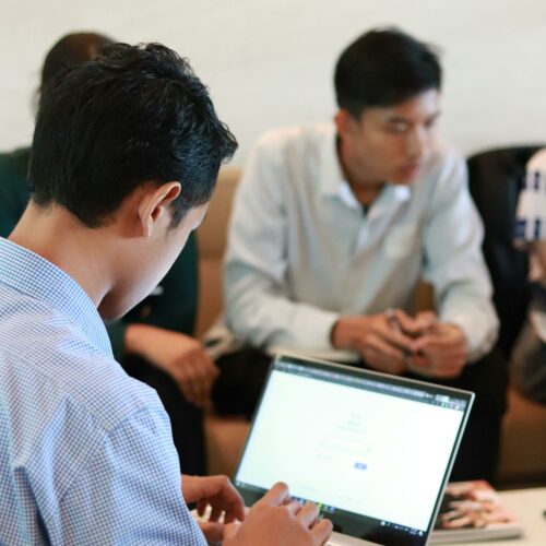 A group of colleagues in a business meeting using laptops for planning and teamwork.