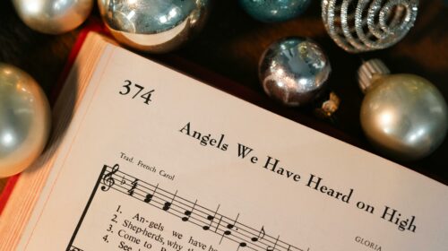 Sheet music for 'Angels We Have Heard on High' with Christmas ornaments.