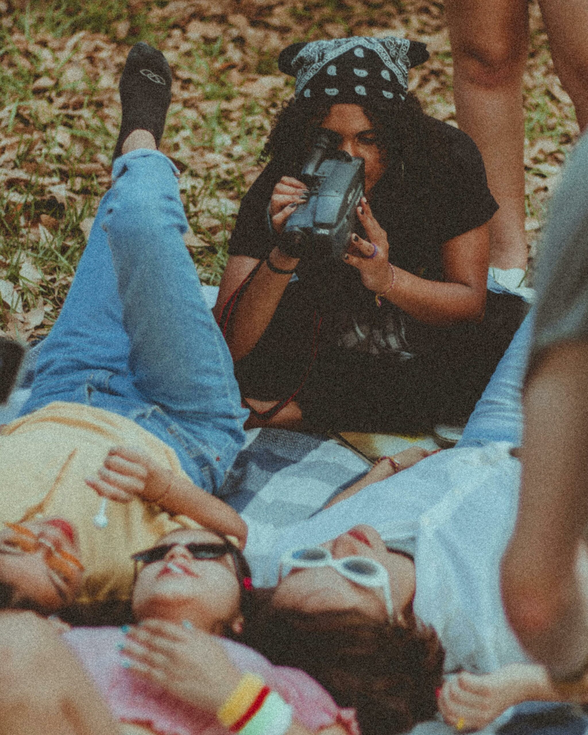 Friends enjoying filming moments together outdoors on a picnic.