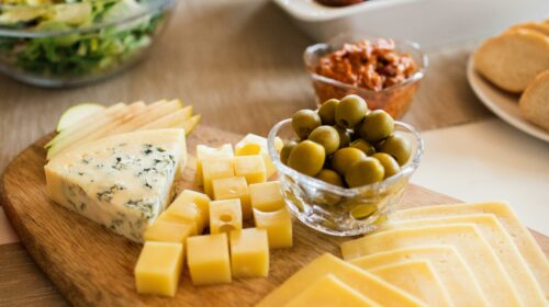 A delicious assortment of cheeses with olives and accompaniments on a wooden platter.