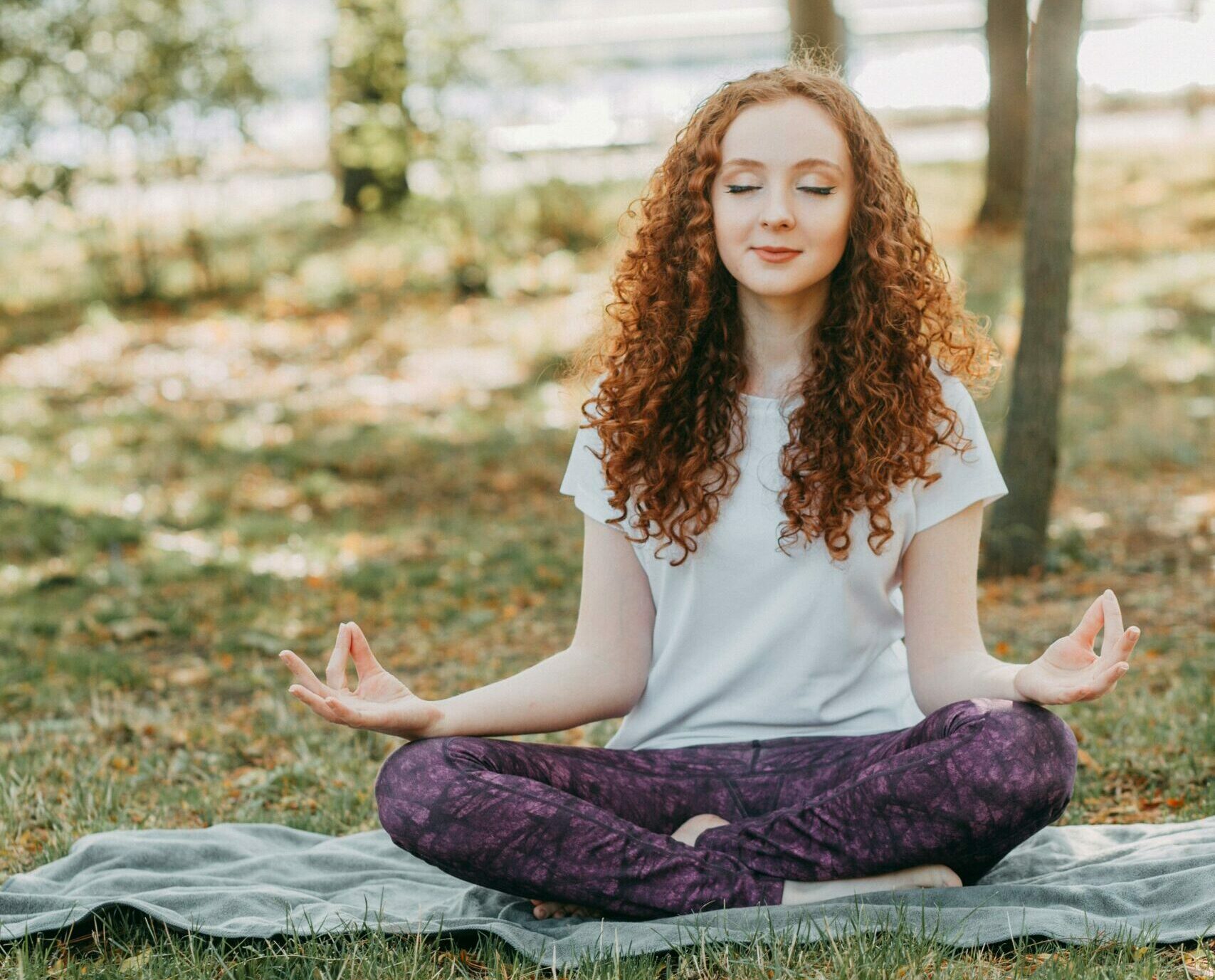 Woman meditating in a serene park during springtime, fostering relaxation and mental wellness.