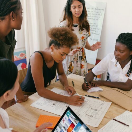 Group of women collaborating on a creative project in a modern office environment.