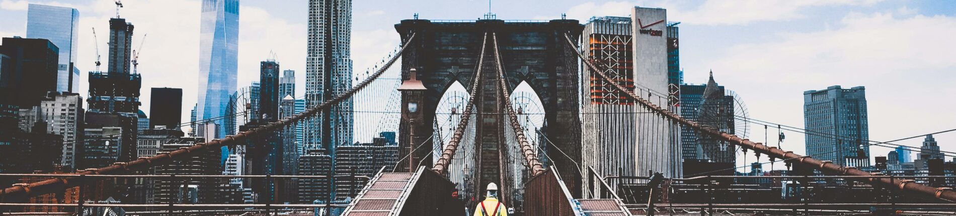 Iconic Brooklyn Bridge view with New York City skyline and construction worker.