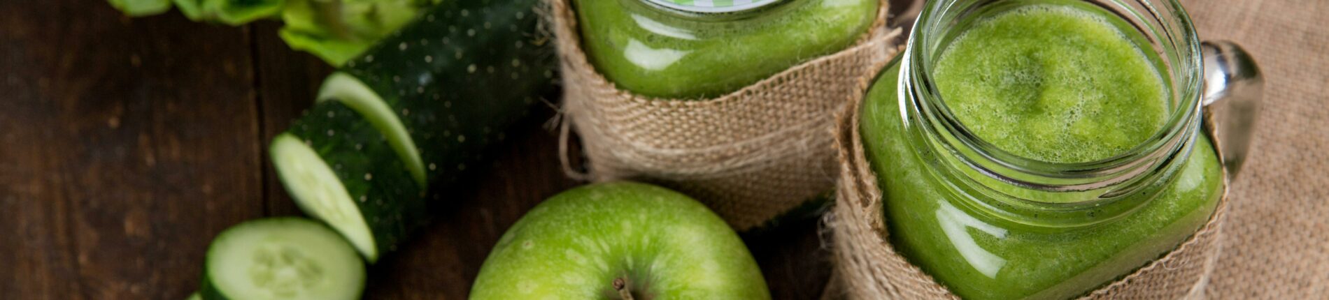 Refreshing green smoothie made with apple, cucumber, and lettuce served in mason jars on wooden background.