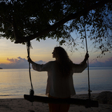 Femme assise sur une balançoire en face de la mer