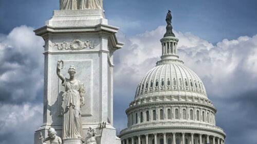 US Capitol building with Peace Monument statue under dramatic clouds.